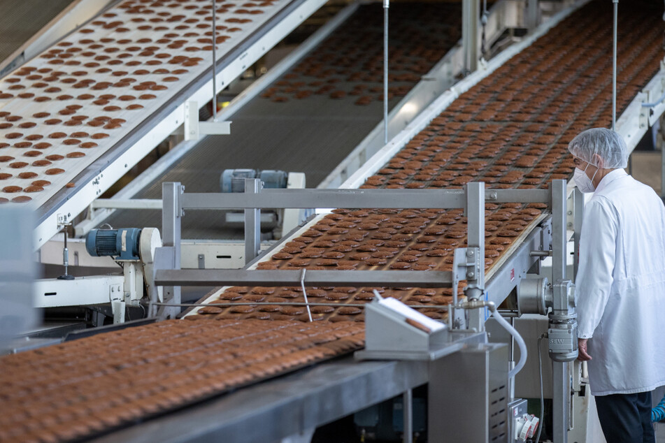 Frisch gebackene Lebkuchen laufen auf einem Band aus einem Ofen in der Produktion des Lebkuchenherstellers Schmidt in Nürnberg.