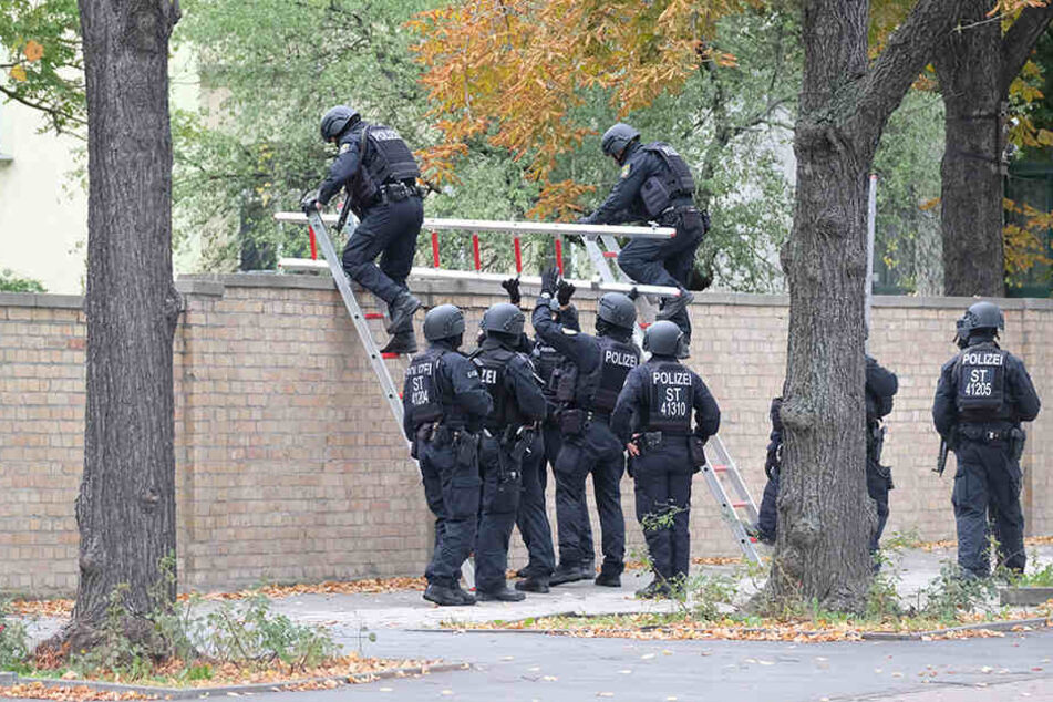 Polizisten mit Schutzhelmen übersteigen eine Mauer am jüdischen Friedhof. Bei Schüssen sind zwei Menschen getötet worden.
