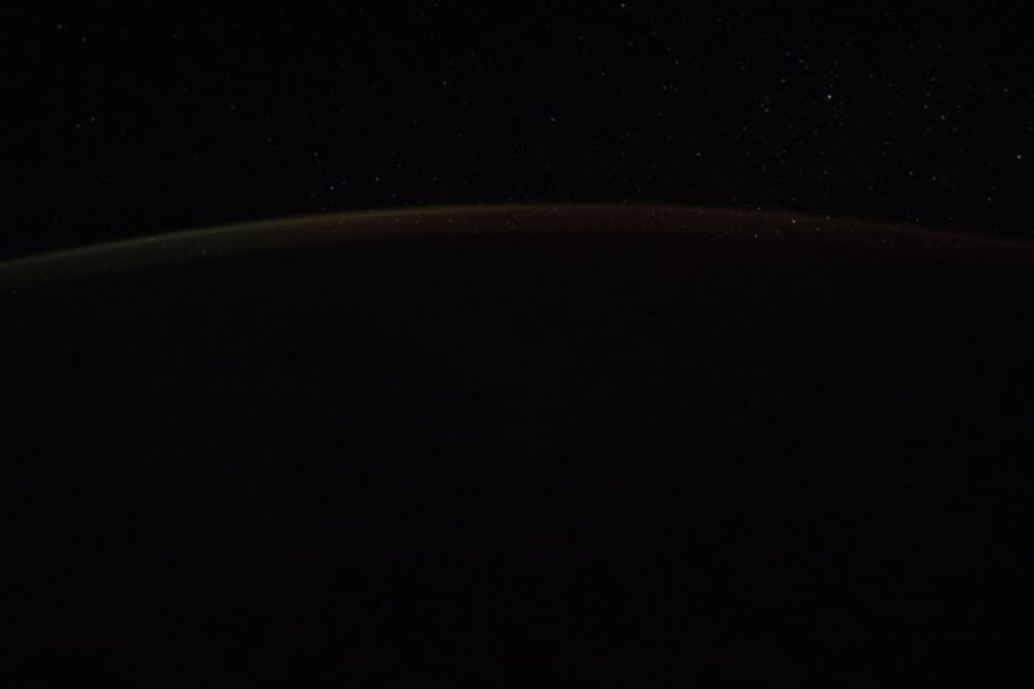 Wer genau hinsieht, sieht einen hellen Streifen am Horizont der Erde.