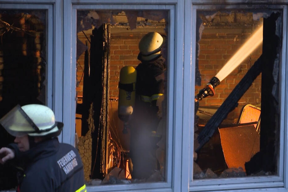 Ein Feuerwehrmann löscht letzte Brandreste in der Hamburger Grundschule.
