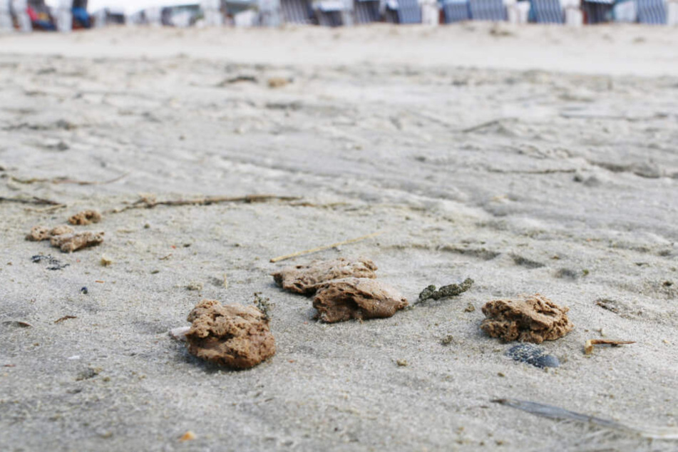 Die Klumpen liegen in nahen Abständen am Strand nahe der Strandkörbe.
