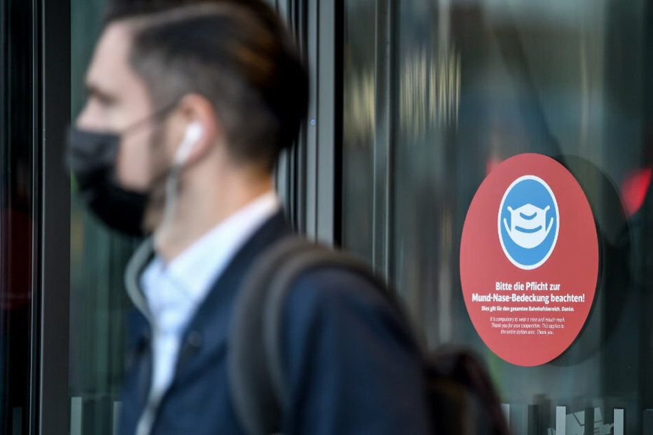 Am Eingang vom Berliner Hauptbahnhof hängt ein Schild mit der Aufschrift "Bitte die Pflicht zur Mund-Nase-Bedeckung beachten!".