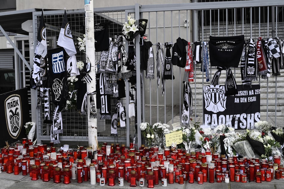 Gedenkstätte vor dem Toumba-Stadion: Schals hängen an den Gitterstäben, Kerzen liegen auf dem Boden.