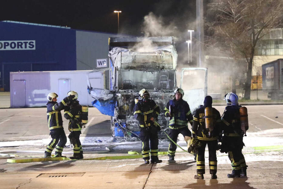 Die Feuerwehrkräfte stehen vor dem ausgebrannten Führerhaus.