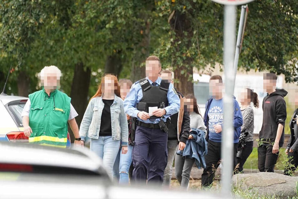 Ein Polizist führt die Schüler zum Sammelplatz.