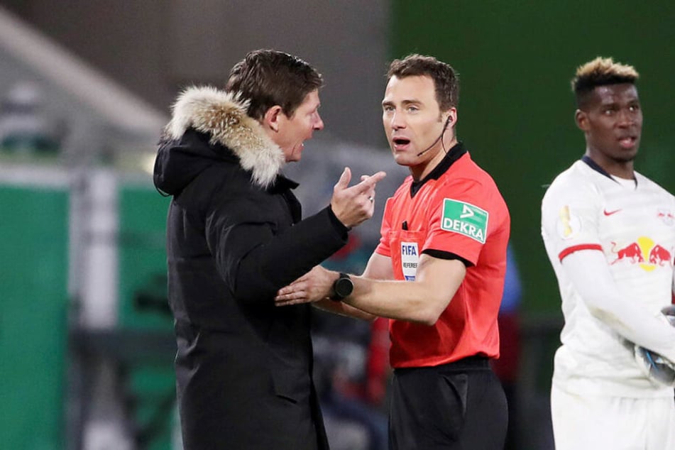 Schiedsrichter Felix Zwayer (r.) musste Wolfsburgs Trainer Oliver Glasner erklären, weshalb er das Handspiel von Yussuf Poulsen nicht abgepfiffen hat.