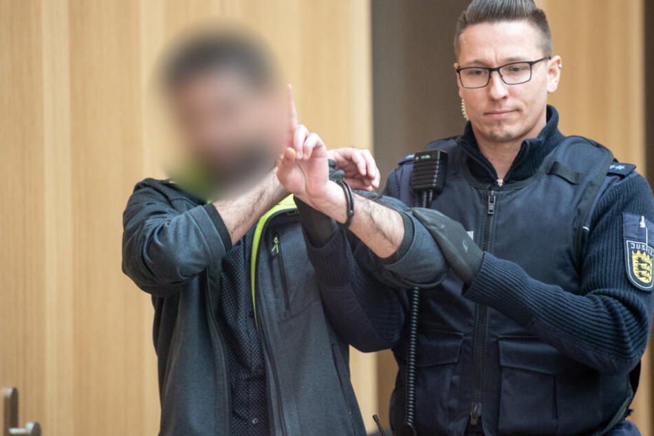 Dieser Angeklagte gestikuliert mit den Händen, während er in den Gerichtssaal gebracht wird.