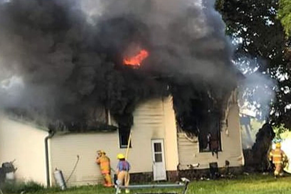 Feuerwehrleute versuchen das Feuer in einem Haus zu löschen.