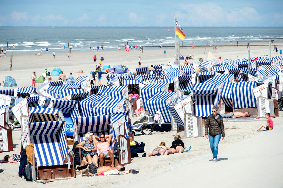 Urlaubsgäste sitzen bei sonnigem Wetter in ihren Strandkörben.