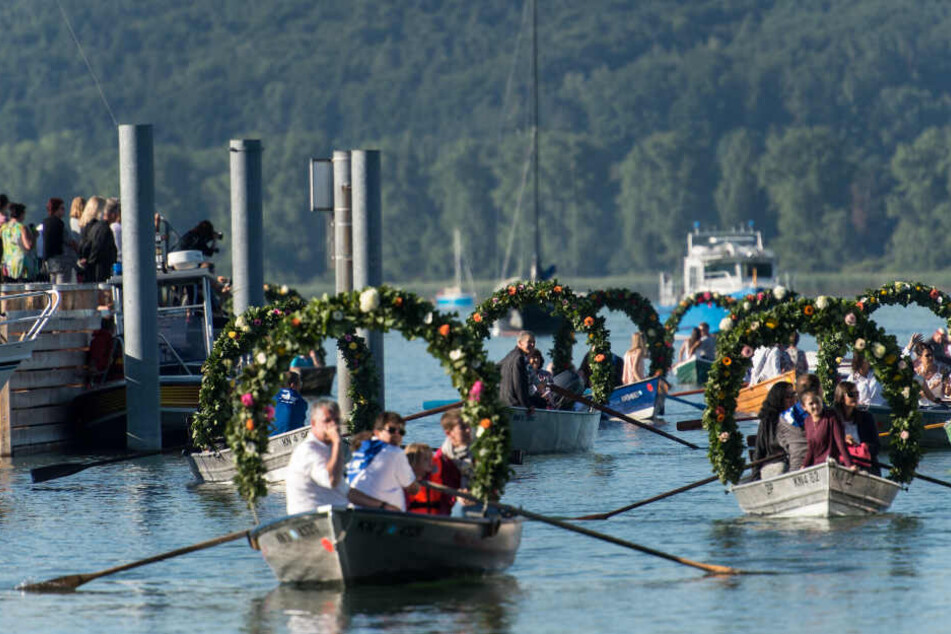 Mit Blumenkränzen geschmückte Boote fahren in den Hafen von Radolfzell am Bodensee während der Mooser Wasserprozession ein. (Archivbild)