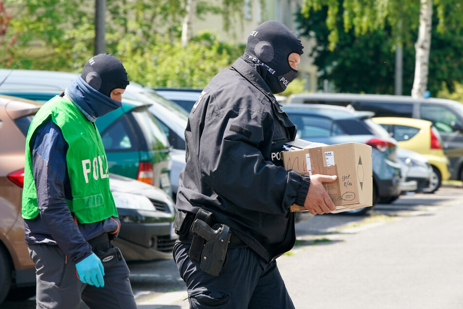 Bundespolizisten tragen in einer Kiste gesicherte Unterlagen aus einem Haus.