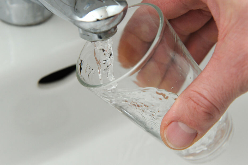 Wasser läuft aus einem Wasserhahn in ein Glas.