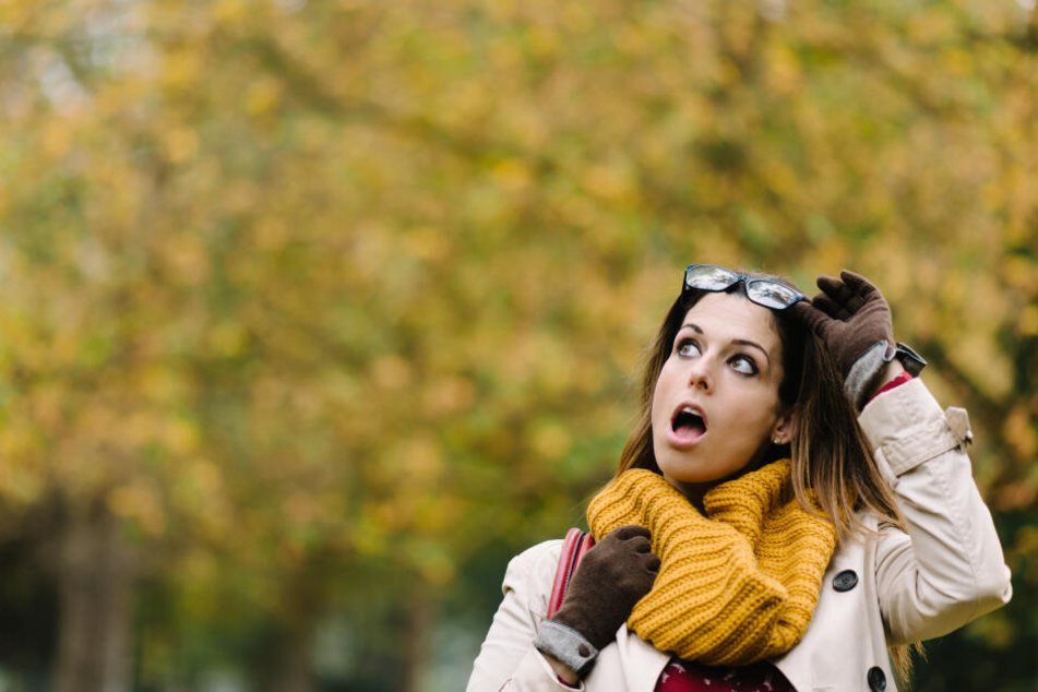 Eine Frau schaut erschreckt auf das herannahende Wetter. (Symbolbild)