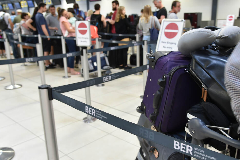 Urlauber stehen im Flughafen Berlin-Schönefeld an den Check-in Schaltern.
