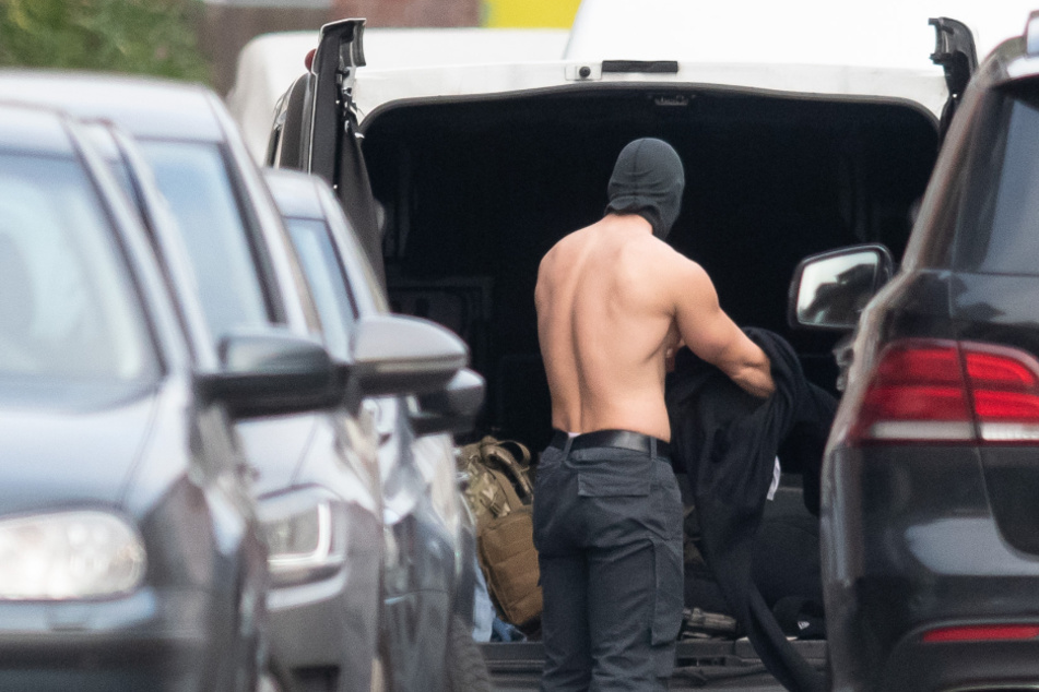 Nach der beendeten Geiselnahme zieht sich ein Polizist an seinem Kofferraum um.