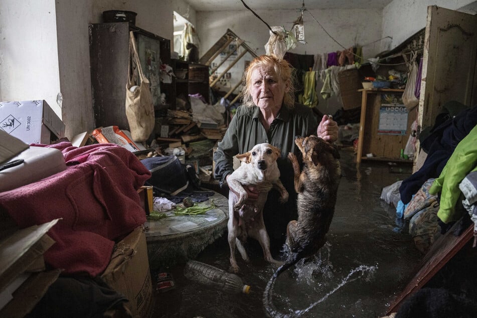 Eine Anwohnerin hält ihre Haustiere im Arm, während sie in ihrem Haus steht, das überflutet wurde.