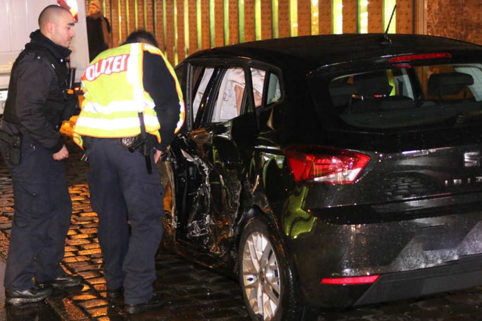 Polizisten betrachten den demolierten Wagen.
