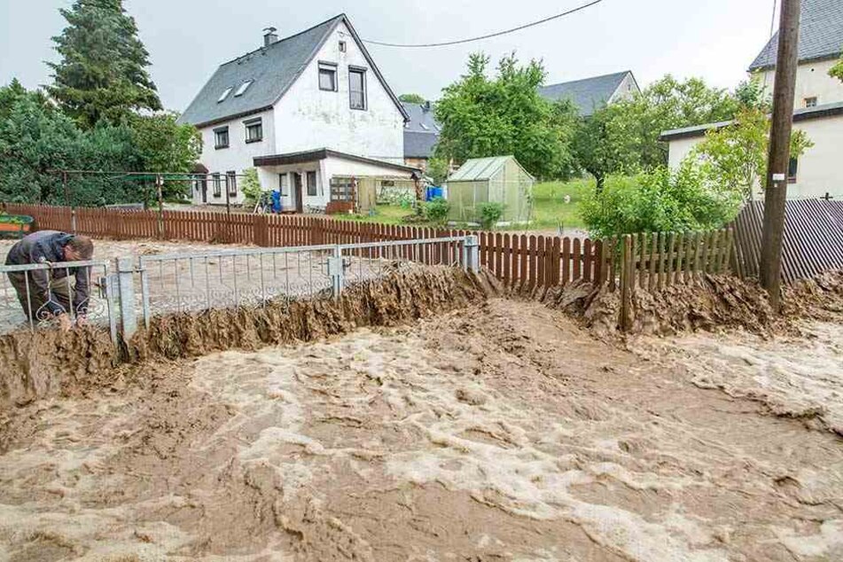 Braune Wassermassen wälzen sich nach heftigen Regenfällen am Samstag durch Gehringswalde im Erzgebirge.