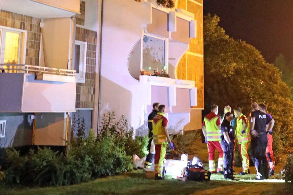Feuerwehrleute und Polizisten stehen vor dem Hochhaus in Rostock.