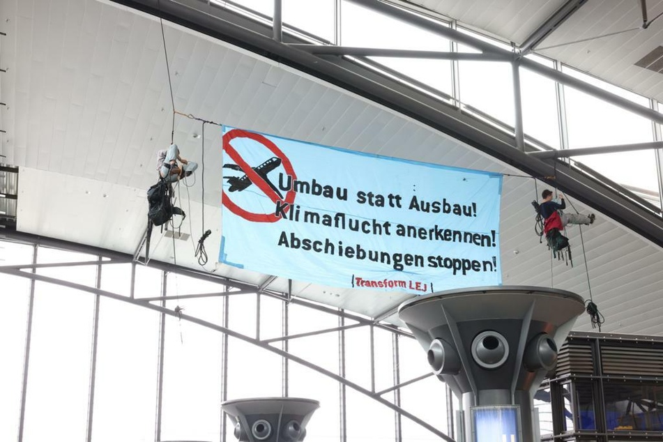 Im Check-In-Bereich des Flughafens seilten sich Demonstranten vom Dach ab und hängten ein Plakat auf.