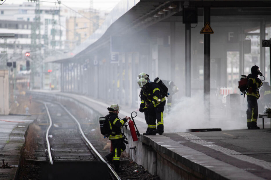 Feuerwehrleute mit einem Feuerlöscher an den Gleisen.