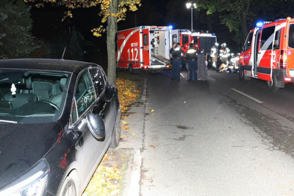 Im Hintergrund kümmern sich die Rettungskräfte um den leblosen Motorradfahrer. Im Vordergrund ist der am Unfall beteiligte Renault zu sehen. Man erkennt deutlich die Stelle, an der der Biker den Wagen gestreift hat.