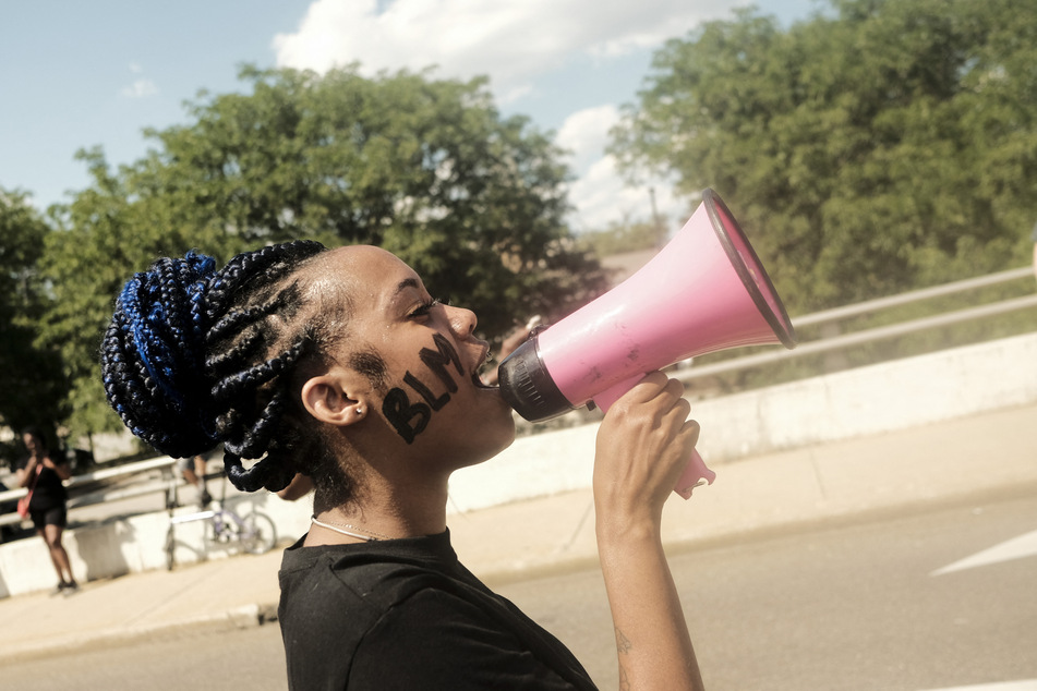 A Black Lives Matter supporter speaks into a megaphone during a rally outside Akron City Hall in July 2022 to protest the police killing of Jayland Walker.