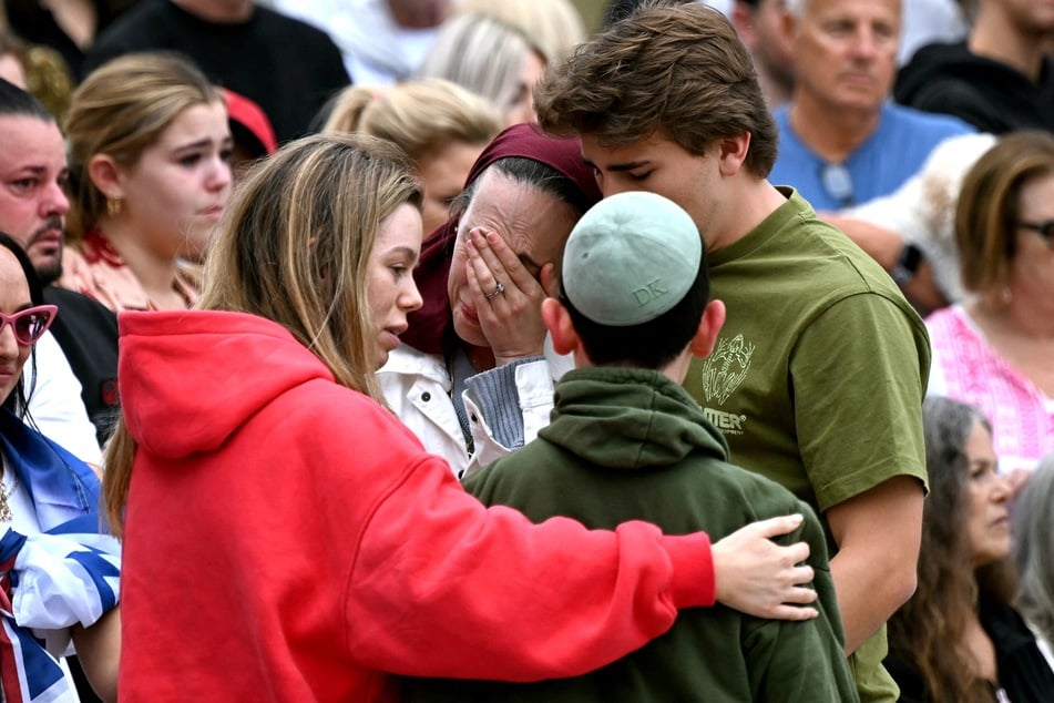 Family members of victims react as they stand with other mourners near tributes at the Bondi Pavilion in memory of the victims of a shooting at Bondi Beach, in Sydney, on Tuesday.