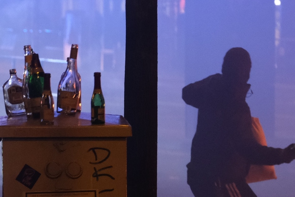 Ein Mann wirft in der Silvesternacht mit einer Flasche in Richtung von Polizisten.