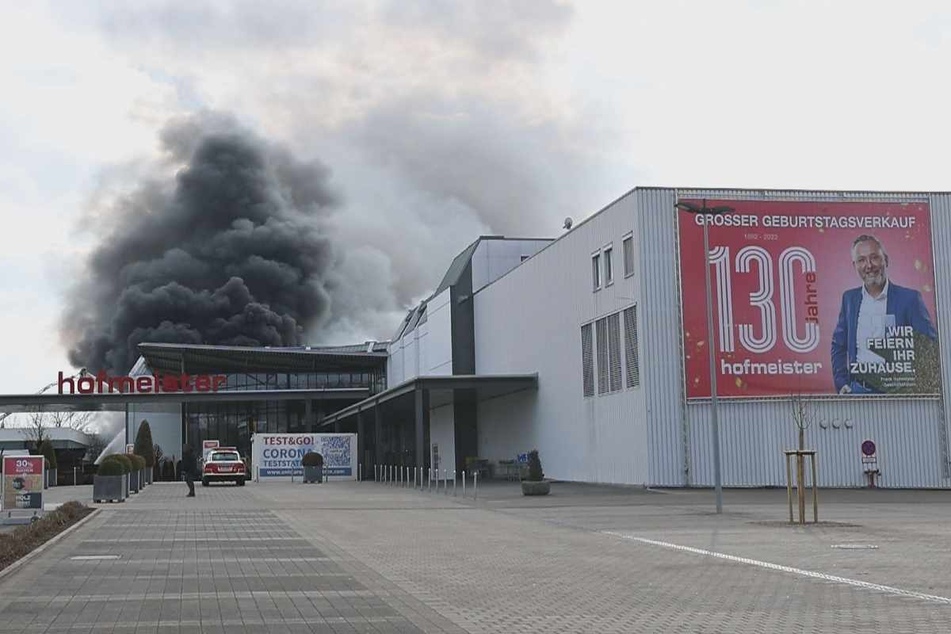 Anlässlich des 130. Geburtstages sollte ein verkaufsoffener Sonntag die Kundschaft nach Bietigheim-Bissingen locken. Dieses Plakat an der Fassade erinnert noch daran, während sich dunkler Rauch in den Himmel erhebt.