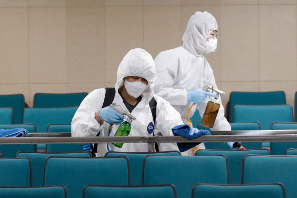 Südkorea, Seoul: Arbeiter in Schutzanzügen sprühen Desinfektionsmittel als Vorsichtsmaßnahme gegen die Ausbreitung des neuen Coronavirus in einer Sporthalle.