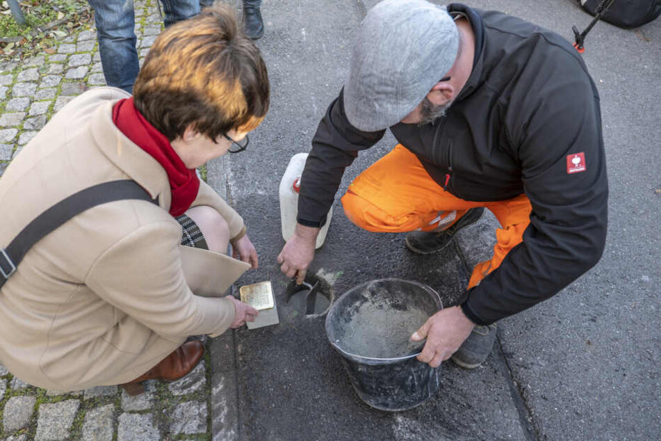 Der erste von 21 Stolpersteinen wird in den Boden eingelassen.