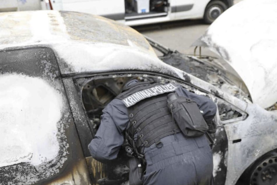 Beamte der Kriminalpolizei untersuchen den ausgebrannten Wagen der Bau-Firma Hentschke.