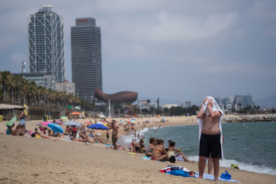 Spanien, Barcelona: Ein Mann trocknet sich mit einem Handtuch am Strand von Barceloneta ab.