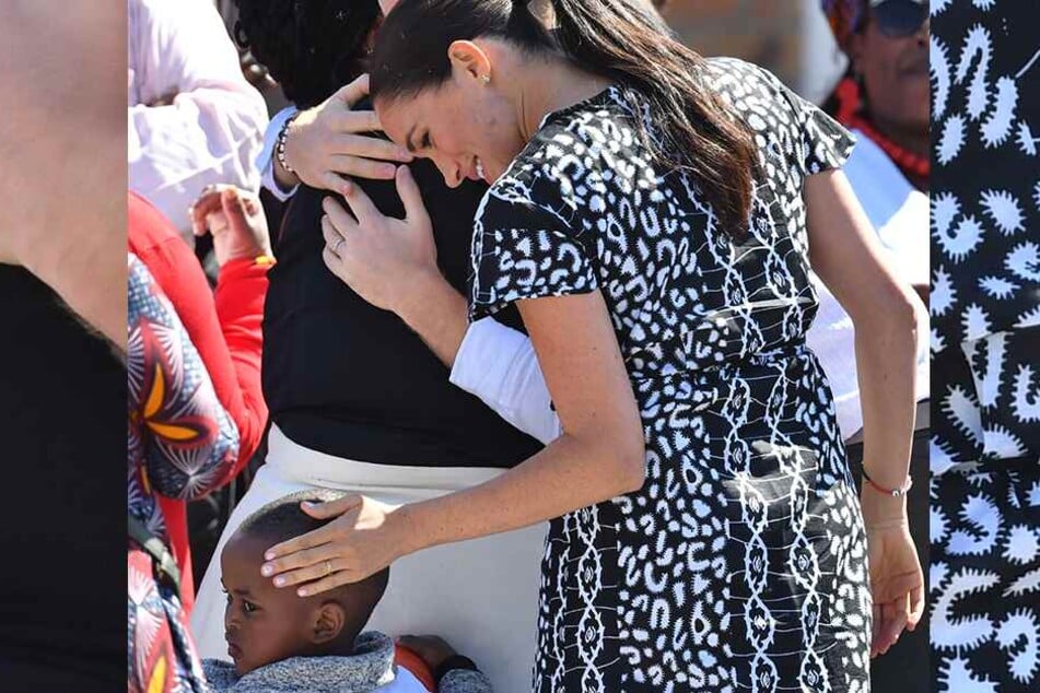 Meghan (38), Herzogin von Sussex, streicht einem Kind über den Kopf, während der britische Prinz Harry (35), dahinter eine Frau umarmt.
