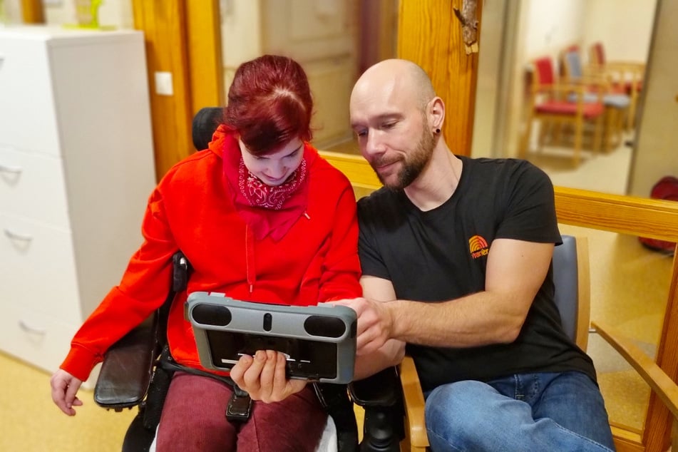 Heilerziehungspfleger (m/w/d) arbeiten mit modernen Tablets, um mit den Klienten zu kommunizieren.
