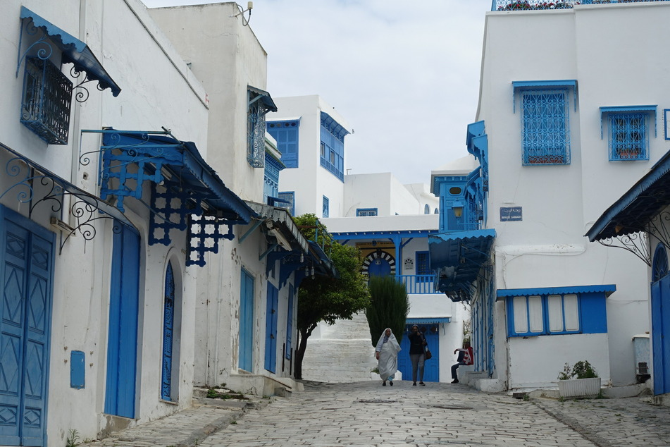 Passanten gehen auf einer Straße in der verlassenen Stadt Sidi Bou Said, einer Touristenattraktion und Künstlerdorf etwa 20 km nordöstlich von Tunis. Tunesiens Tourismus hat wegen der Corona-Krise einen starken Einbruch erlebt.