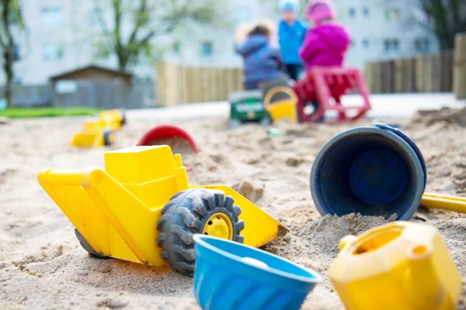 Spielzeug liegt in einem Sandkasten in einer Kindertagesstätte.