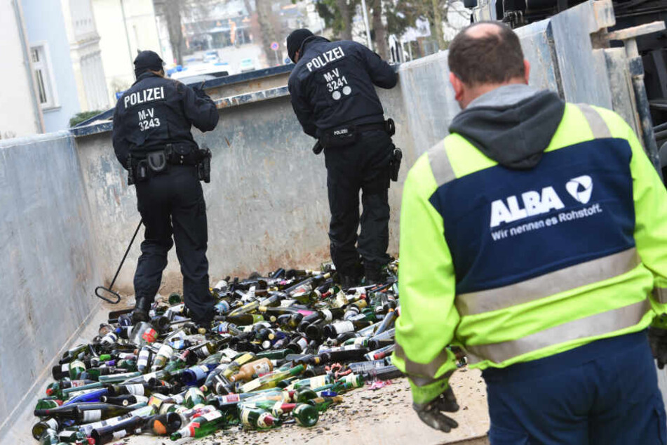 Polizisten durchsuchen in Zinnowitz einen Altglascontainer. Im ungelösten Mordfall einer 18-Jährigen sucht die Polizei nach neuen Spuren auf der Insel Usedom.