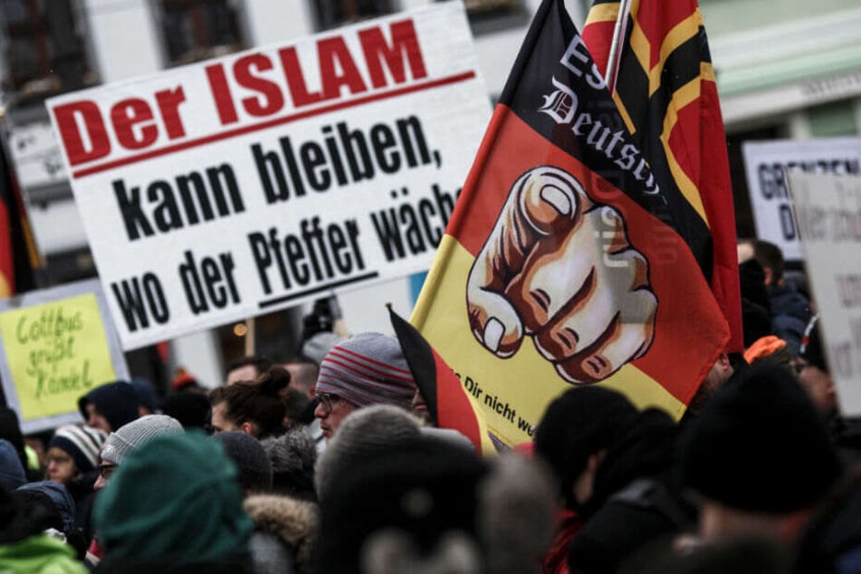 Demonstranten der rechten Szene halten in Cottbus Plakate und Fahnen hoch. (Archivbild)