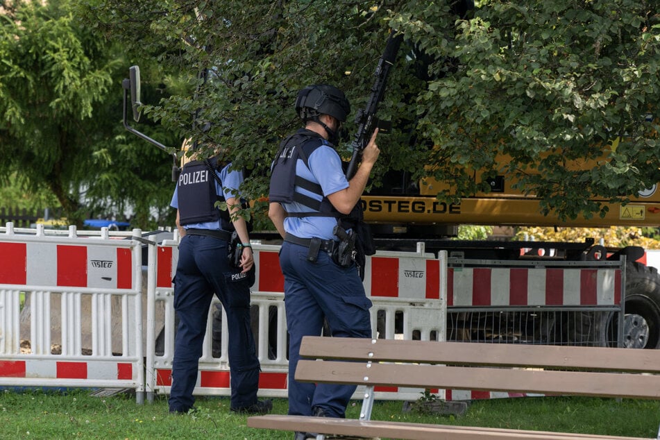 Behelmt und mit Maschinenpistole im Anschlag nähern sich Polizisten dem Garten der wehrhaften Rentnerin.