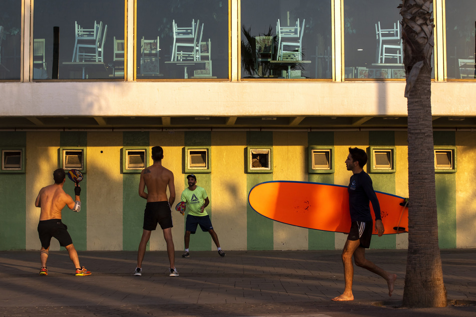 Israel, Tel Aviv: Männer spielen Paddelball neben einem geschlossenen Hotel. Das Land befindet sich in einem dreiwöchigen Lockdown aufgrund der Corona-Pandemie.