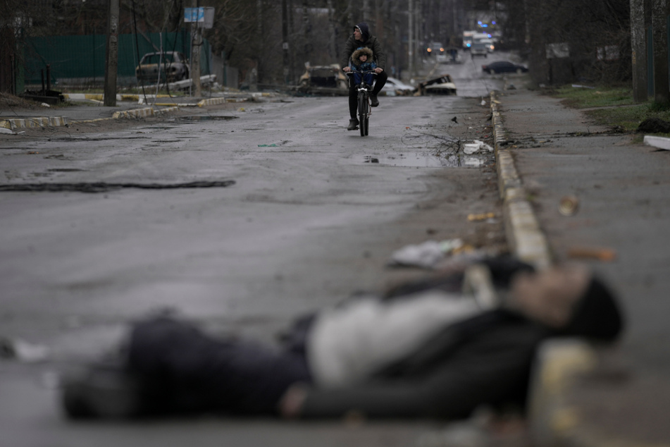Die Bilder aus der Ukraine sind schrecklich: Ein Mann und ein Kind fahren auf einem Fahrrad, während die Leiche eines Zivilisten auf der Straße im ehemals russisch besetzten Kiewer Vorort Butscha liegt.