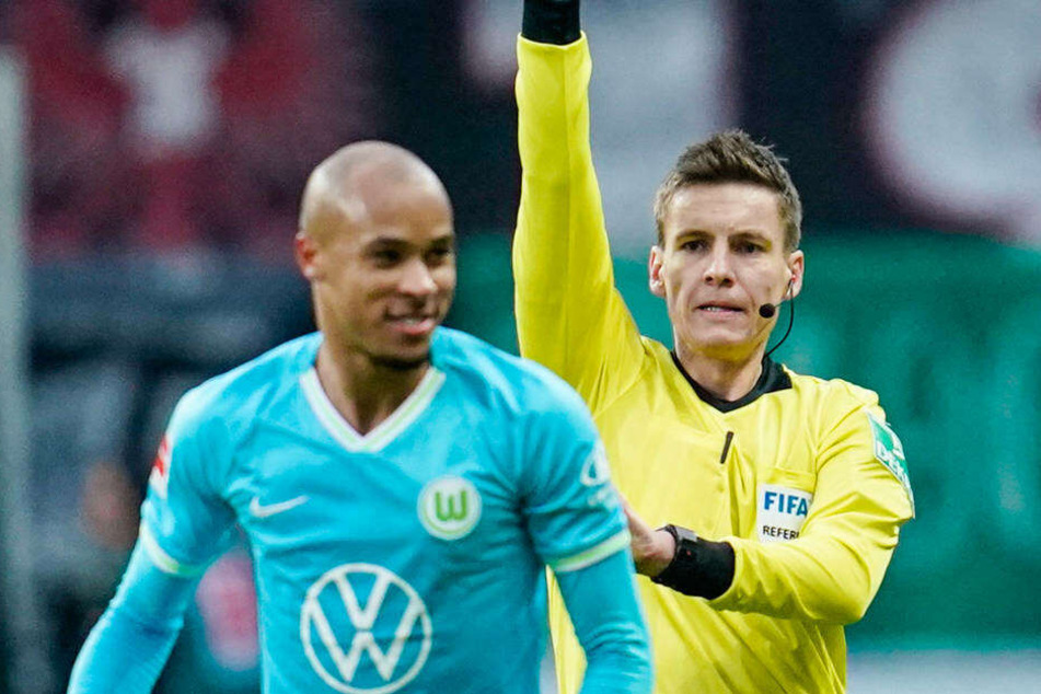 Schiedsrichter Daniel Siebert zeigt Wolfsburgs Marcel Tisserand die gelbe Karte, kurz danach sah der Verteidiger gelb-rot.