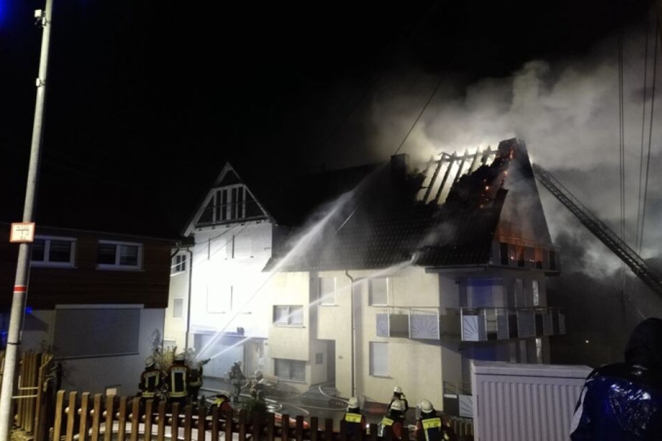 Das brennende Mehrfamilienhaus in Weil der Stadt wird von Feuerwehrleuten gelöscht.