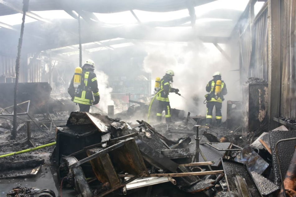 Feuerwehrleute bei der Arbeit in der abgebrannten Lagerhalle.