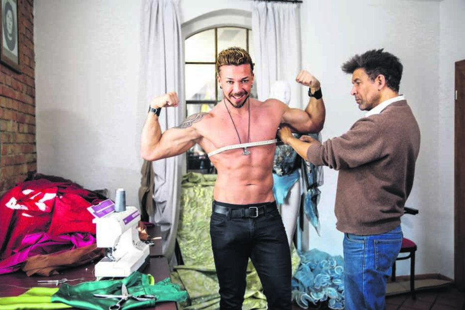 Stripper Damian (l.) spannt die Muckis an, damit Dyona Lorr ordentlich Maß nehmen kann.