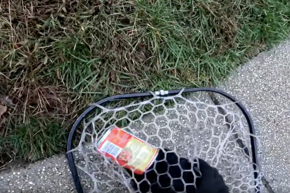 John used a net and gloves to trap and free the cat with the can stuck on its head.