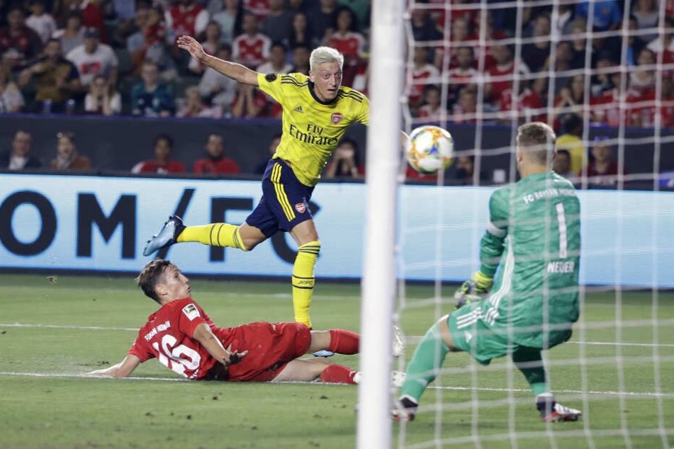 Münchens Jonas Kehl (l) und Torhüter Manuel Neuer (r) gegen Arsenals Mesut Özil.