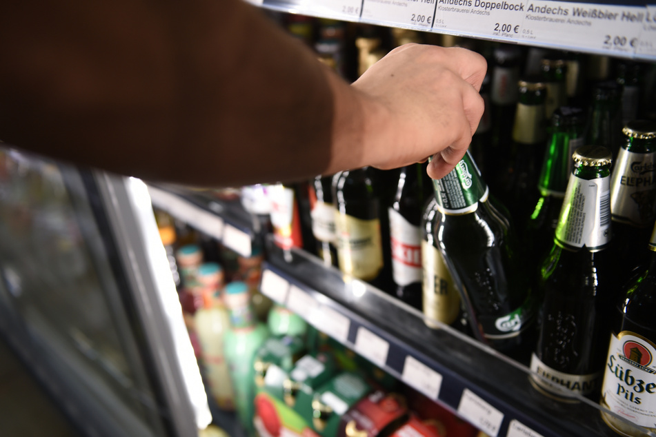 Ein Mann holt eine Flasche Bier aus einem Kühlschrank in einem Spätkauf.